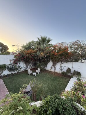 A patio area with a white wall, a small table, and chairs. - Dar Souad: A haven of peace and Tunisian charm just outside Tunis! (La Marsa)