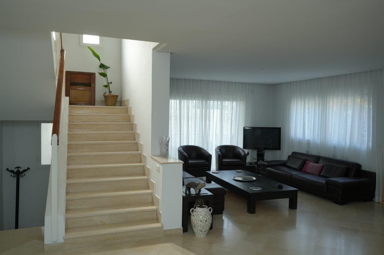 A living room with a staircase, a sofa, a coffee table, and a TV.
