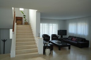 A living room with a staircase, a sofa, a coffee table, and a TV. - Dar Souad: A haven of peace and Tunisian charm just outside Tunis! (La Marsa)