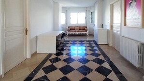 Une pièce spacieuse avec un sol à carreaux, un canapé, un bureau et un radiateur.