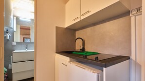 A compact kitchen with a black countertop, white cabinets, and a green cutting board. - Cosy Cabin “Cabane Grenobloise” with Shared Garden (Eybens)