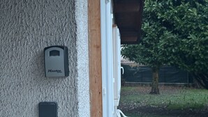 A textured wall with a door, a mailbox, and a small black object. - Cosy Cabin “Cabane Grenobloise” with Shared Garden (Eybens)