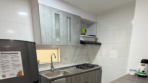 A compact kitchen with a refrigerator, a sink, and a stove. - Comfortable Apartment – Stratum 5 (Manizales)