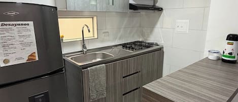 A compact kitchen with a refrigerator, a sink, and a stove.