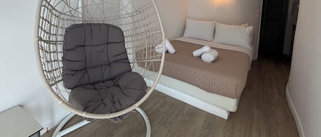Ein Zimmer mit einem Bett, einem Hängesessel und einem kleinen Tisch.