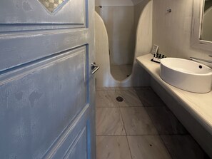 Een badkamer met een wit wastafelmeubel, een spiegel en een douche.