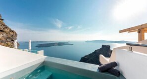 A pool with a view of the sea and a cliff, a white chair, and a wooden structure. - DIAMOND on the cliff Hotel &Suites (Santorini)