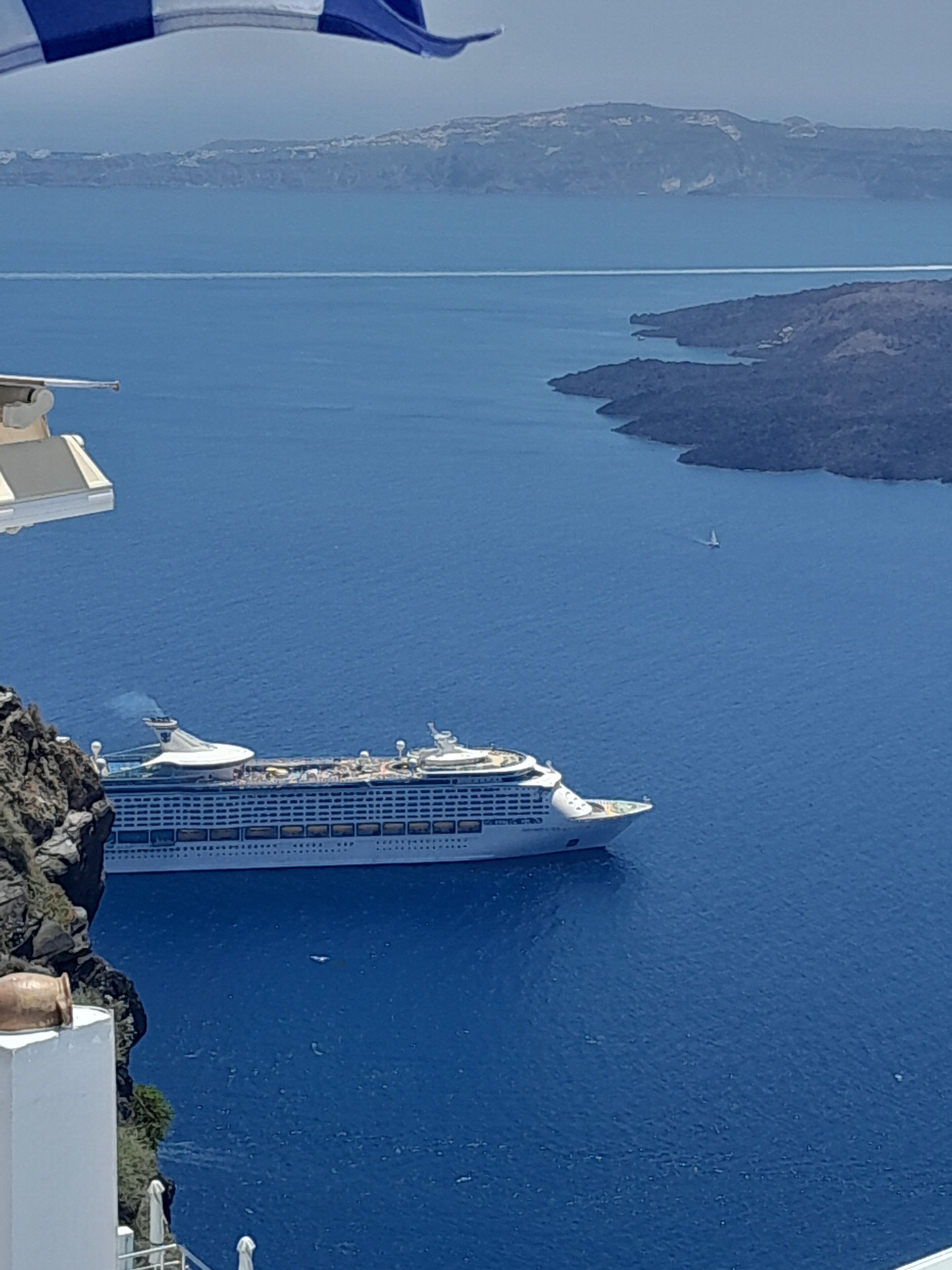 Un gran crucero amarrado en un puerto, con una vista clara del agua circundante y la tierra distante.
