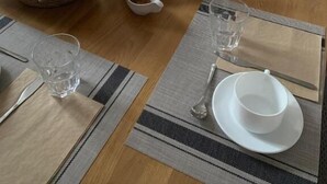 Mesa de jantar posta para uma refeição, com pão, manteiga e acompanhamentos.