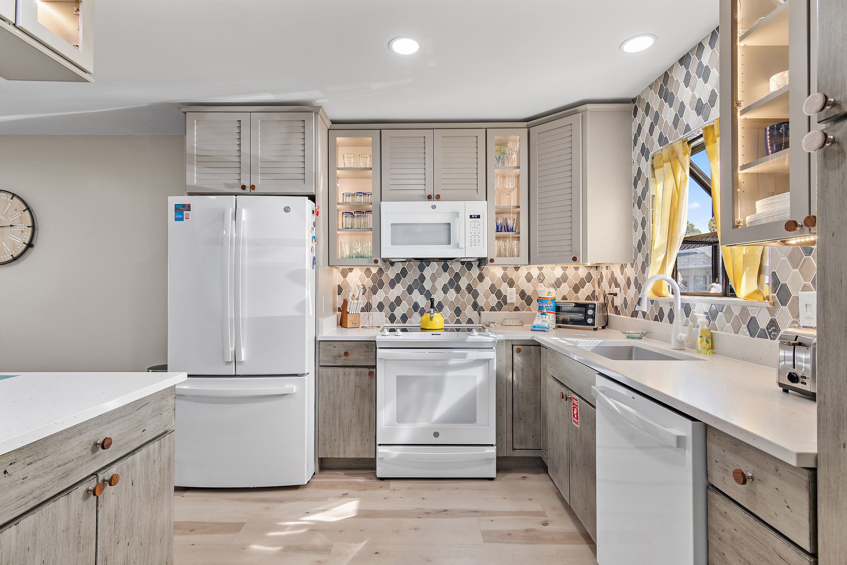A modern kitchen with white appliances, wooden cabinets, and a tiled backsplash.