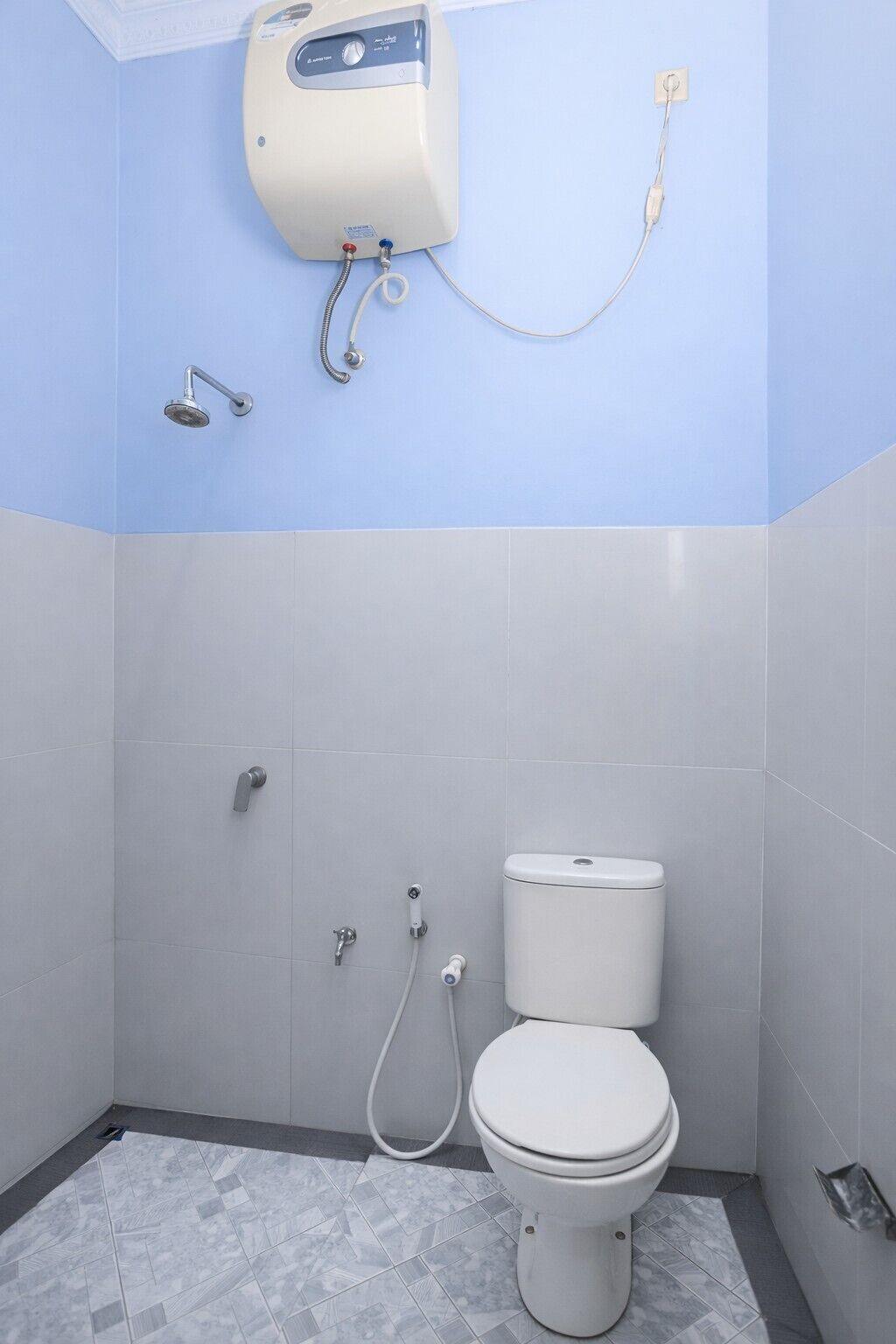 A bathroom with a toilet, a shower, and a water heater mounted on the wall.