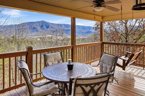 Ein überdachter Außenbereich mit Tisch und Stühlen mit Blick auf eine Berglandschaft.