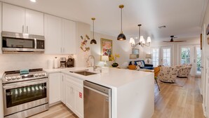 A modern kitchen with white cabinetry, stainless steel appliances, and a large island. - Angel Fish Cove | Updated Townhome Retreat Near Duval (Key West)