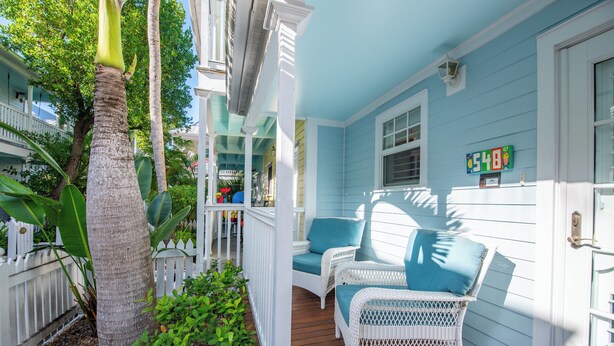 A porch with wicker chairs and a white fence. - Angel Fish Cove | Updated Townhome Retreat Near Duval (Key West)