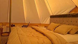 A tent with a bed, a chair, and a small table. - ESCAPE cAMp Tent #2 (Bidiyah)