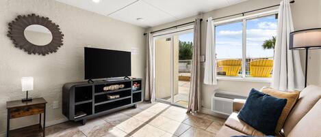Unwind in your bright living room with modern furnishings and direct patio access, where sunny yellow chairs beckon you outdoors.