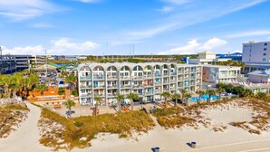 A beachfront hotel with multiple balconies, a pool area, and a sandy beach. - The Ambassador - Unit C5 - Studio King - On Pool Deck (Panama City Beach)