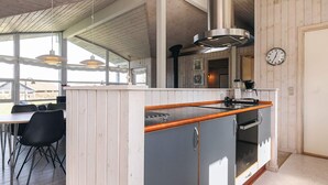 Une cuisine moderne avec des meubles en bois, un four encastré et une grande fenêtre.