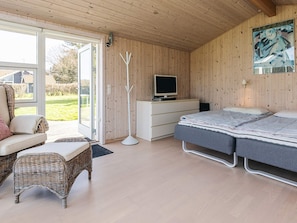 Ein Schlafzimmer mit einem Bett, einem Schreibtisch mit Computer, einem Sessel und einem Fenster.
