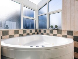 Un baño con una bañera independiente, ventanas con vidrio esmerilado y un revoque de azulejos.