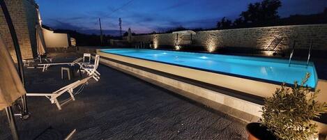 Piscina a l'aire lliure de temporada, para-sols i gandules