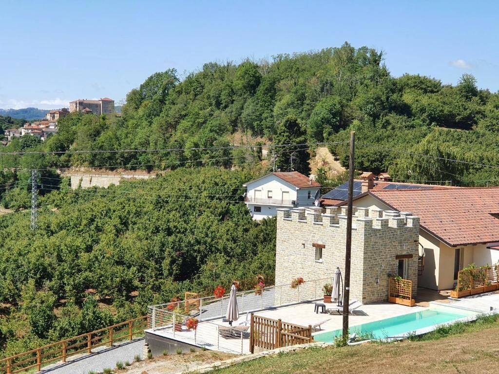 A stone house with a swimming pool, surrounded by lush greenery and hills.