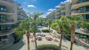 Un hotel con varios balcones, piscina y zonas de estar al aire libre.