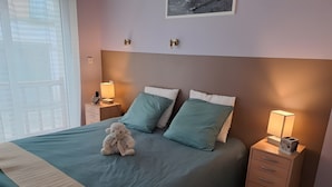 Ein ordentlich bezogenes Bett mit einem Kuscheltier, zwei Nachttische mit Lampen und einer Kommode.