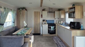 Een compacte keuken met een eethoek, houten kastjes, een inbouwoven en een kleine koelkast.