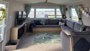 Een gezellig RV-interieur met een bank, tv en uitzicht op het buiten.