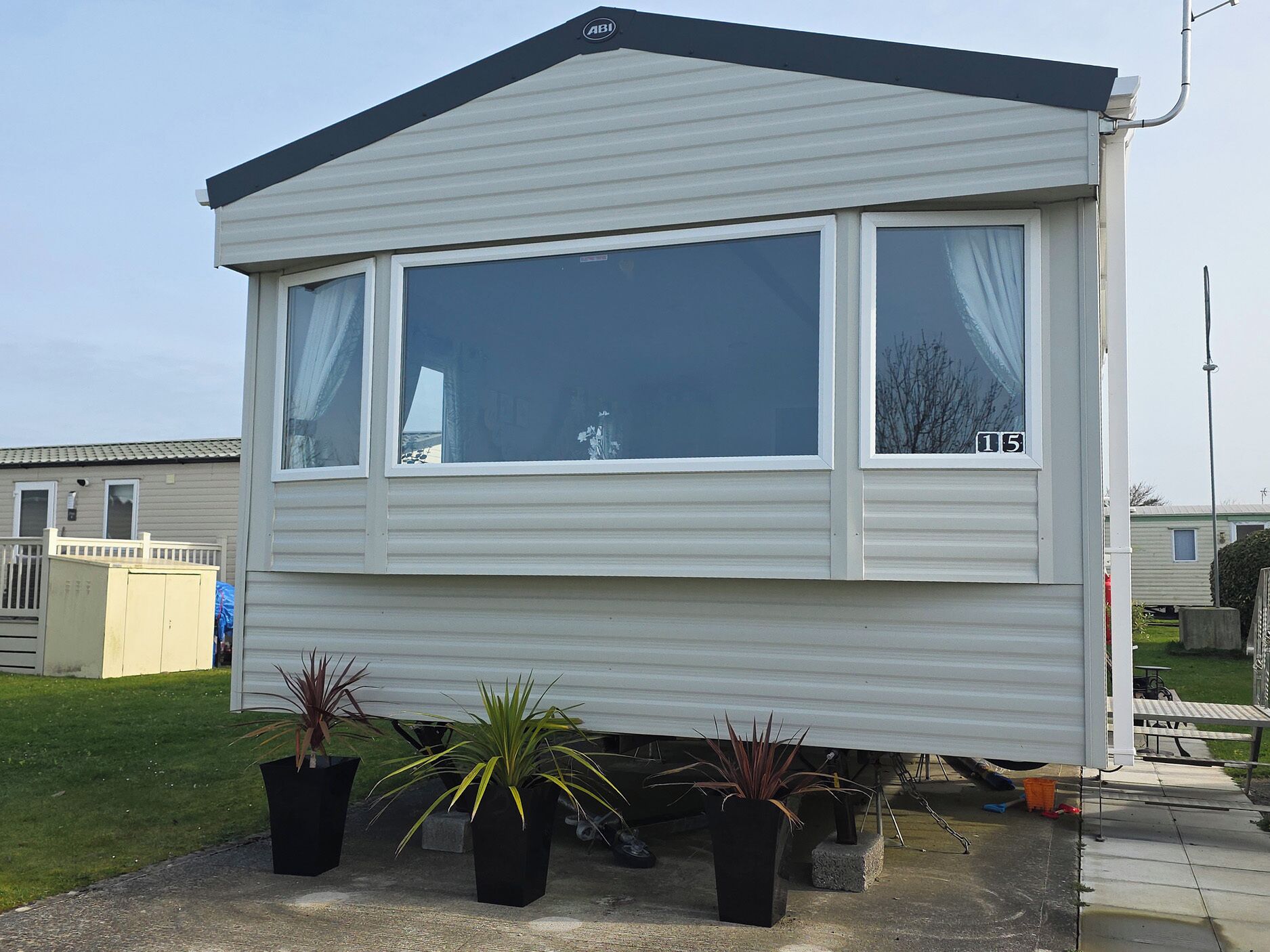 A mobile home with a large window, a small porch, and potted plants.