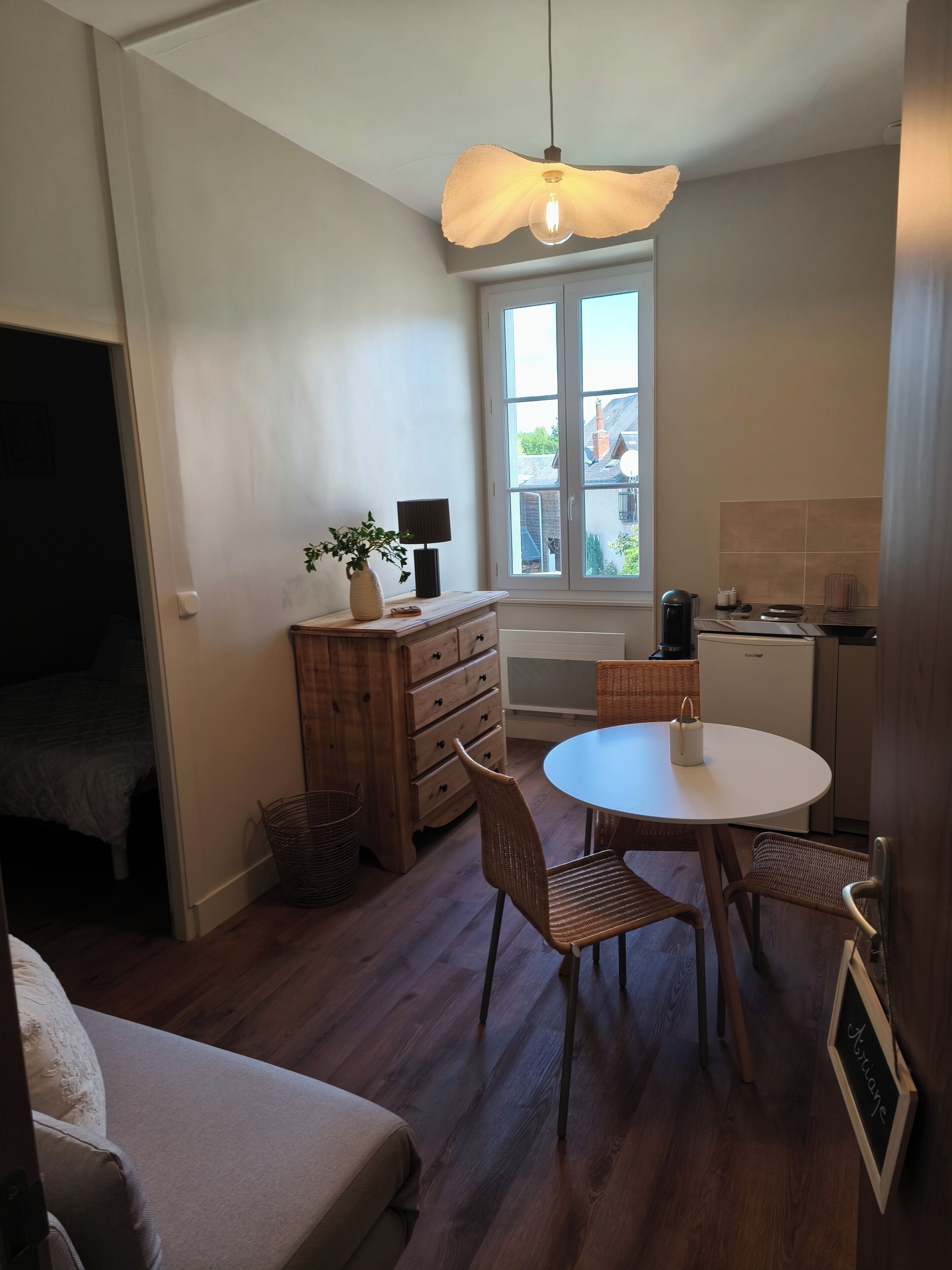 A compact living space with a dining area, kitchenette, and a large window offering a view of the outside.