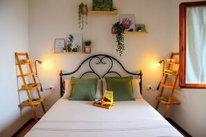 A neatly made bed with green pillows, a tray of snacks, and two wooden ladders on either side. - Bright Flat Over the Hills of Lake Garda (Villanuova sul Clisi)