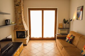 A living room with a fireplace, a sofa, and a television. - Bright Flat Over the Hills of Lake Garda (Villanuova sul Clisi)