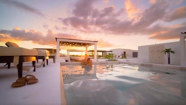 A rooftop pool with a glass enclosure, lounge chairs, and a sunset view. - Work & Relax apto fast wifi (Tulum)