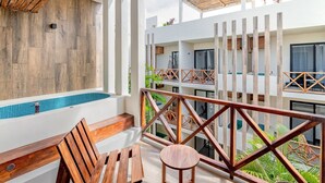 A balcony with wooden furniture, a pool, and a view of the building's interior. - Work & Relax apto fast wifi (Tulum)
