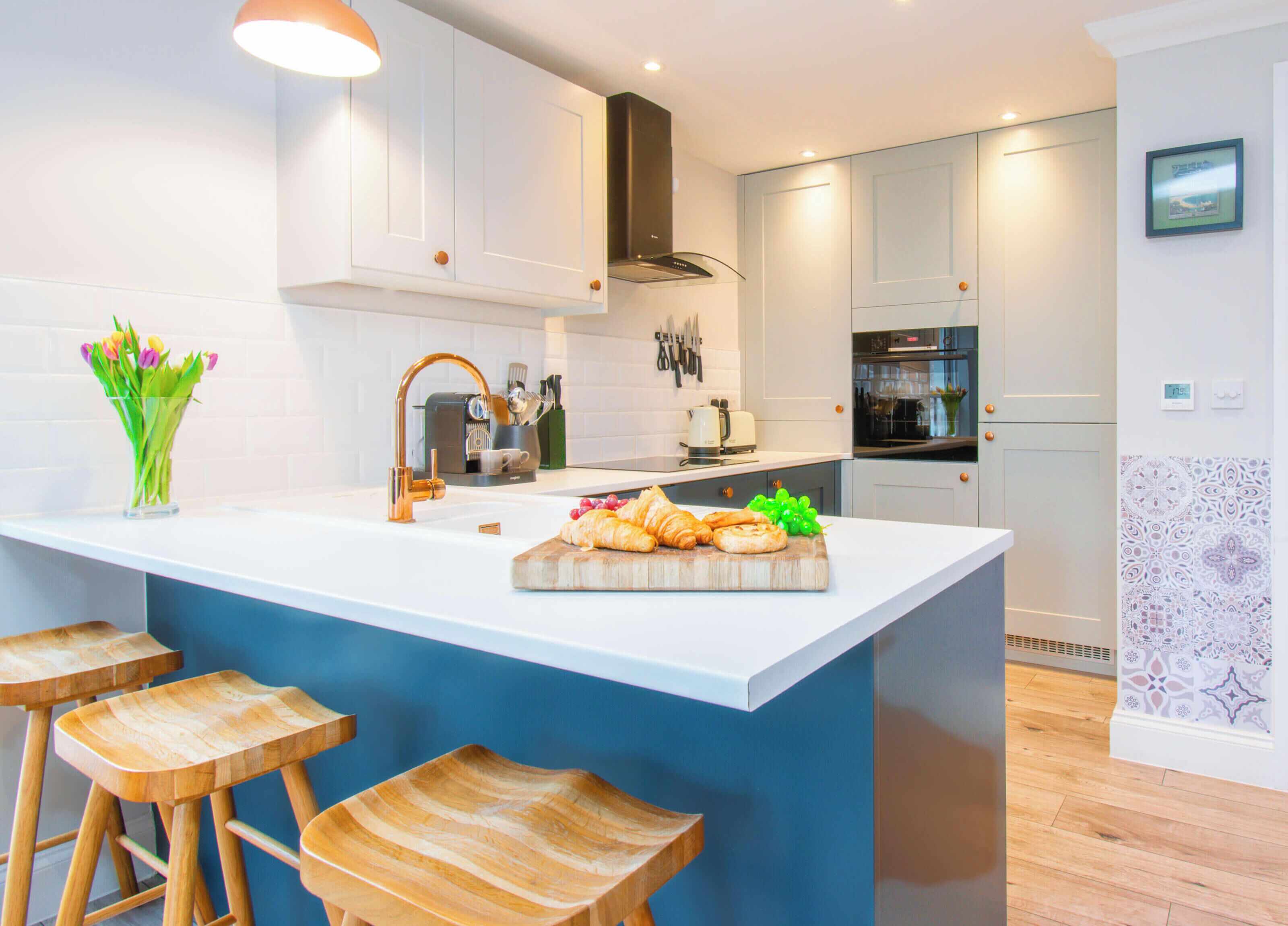 A modern kitchen with a central island, bar stools, and a variety of appliances.
