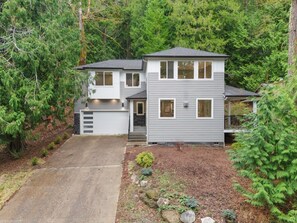 Modern two-story home nestled among towering evergreens with private driveway and landscaped front yard. - Modern 4BR Bellingham Home w/ Deck & Garage (Bellingham)