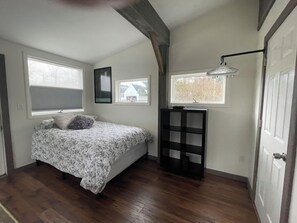 A bedroom with a bed, a nightstand, a window, and a door.