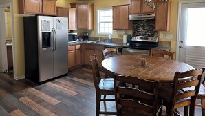 A kitchen with wooden cabinets, a stainless steel refrigerator, a stove, and a dining table with chairs.