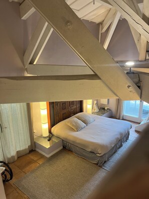 A bedroom with a bed, bedside lamps, a wooden headboard, and a view of the outside through a window. - Le Marais de Capeau, private with pond, swimming pool and leisure facilities (Arles)