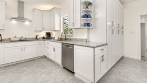 Una cocina moderna con armarios blancos, lavavajillas y encimera de granito.