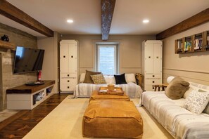 A cozy bedroom with a large bed, two white wardrobes, a TV, and a bookshelf.