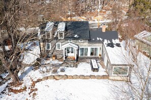 A large house with a covered porch, a stone wall, and a snow-covered yard.