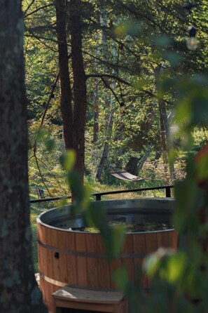 Un bain à remous en bois, entouré d’arbres.