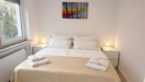 Ein Schlafzimmer mit einem großen Bett, zwei Nachttischen, einem Fenster und einem Bild an der Wand.