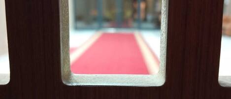 Vista a través de una ventana con alfombra roja, puerta de cristal y marco de madera.