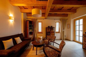 Un salon chaleureux avec un canapé marron, des fauteuils à motifs, une table basse et une bibliothèque.