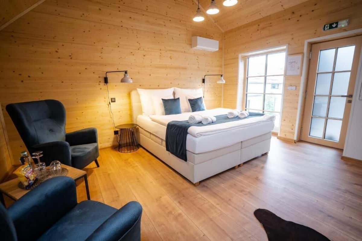 A cozy room with a bed, two armchairs, a small table with drinks, and a window with a view.