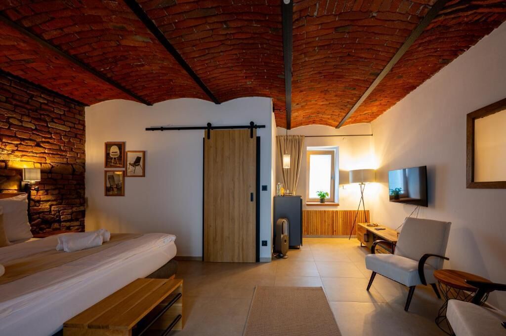 A cozy room with a brick ceiling, a bed, a desk, a chair, and a TV.